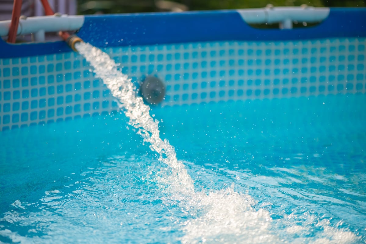 Clean water filling a backyard swimming pool on a sunny day