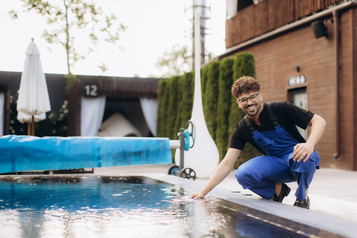 Pool technician checking the water quality of a clear blue swimming pool